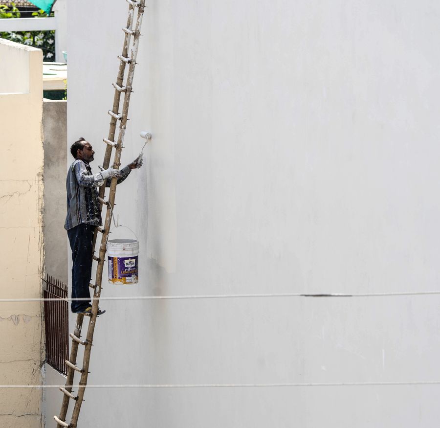 Peintre sur une échelle peignant un mur extérieur