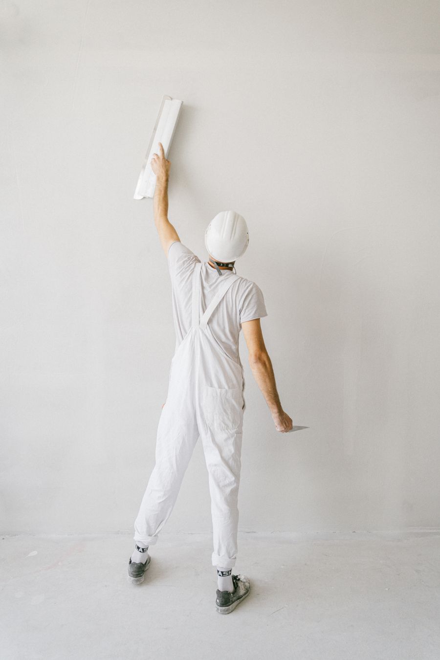Peintre appliquant une couche de peinture blanche au rouleau sur un mur